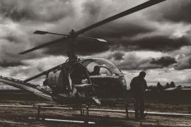 Black and white photo of helicopter and pilot on the ground